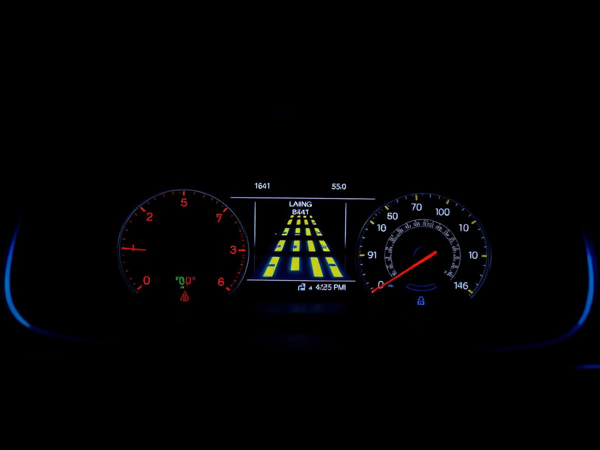 A glowing digital instrument cluster showing lane markings and warning symbols